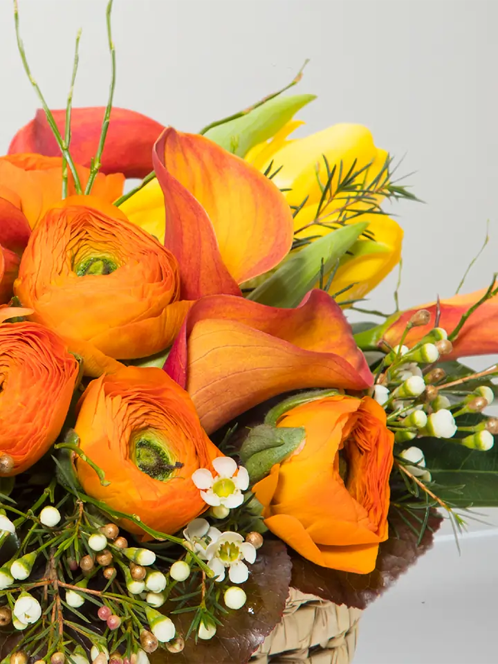 Cesto in vimini di fiori arancio e gialli ranuncoli tulipani calle dettagli